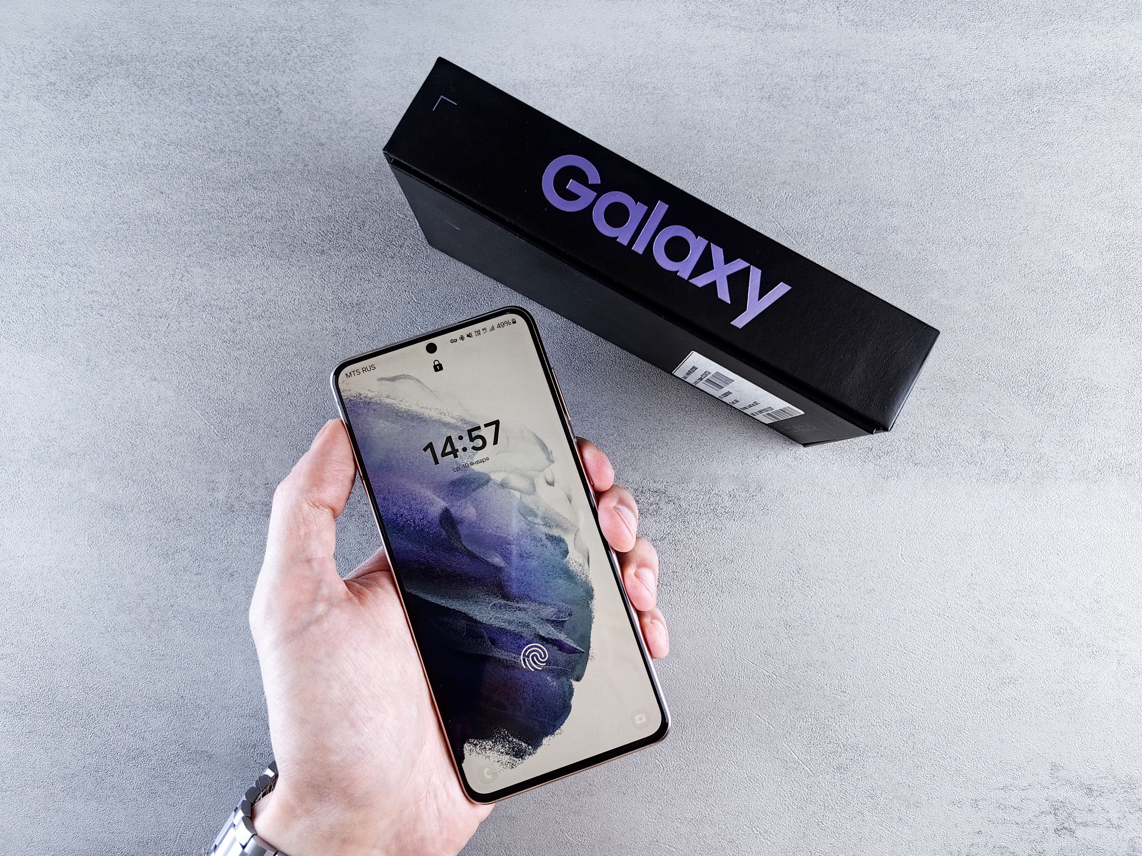 Hand holding a Samsung Galaxy smartphone with its retail box, ready for installing AI writing apps